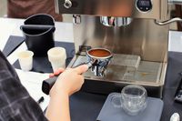 A person holding the portafilter with coffee next to the Lelit Elizabeth Espresso Machine
