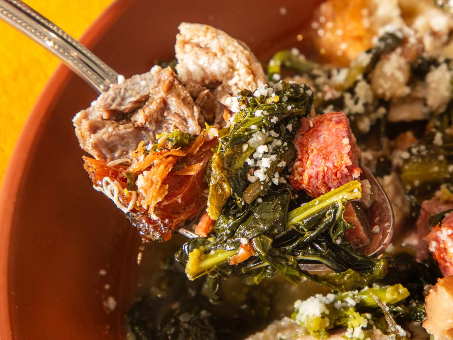 A spoonful of Italian wedding soup featuring meat greens and small pasta in a broth