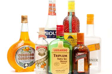 Seven different brands and styles of orange liqueur on a white surface