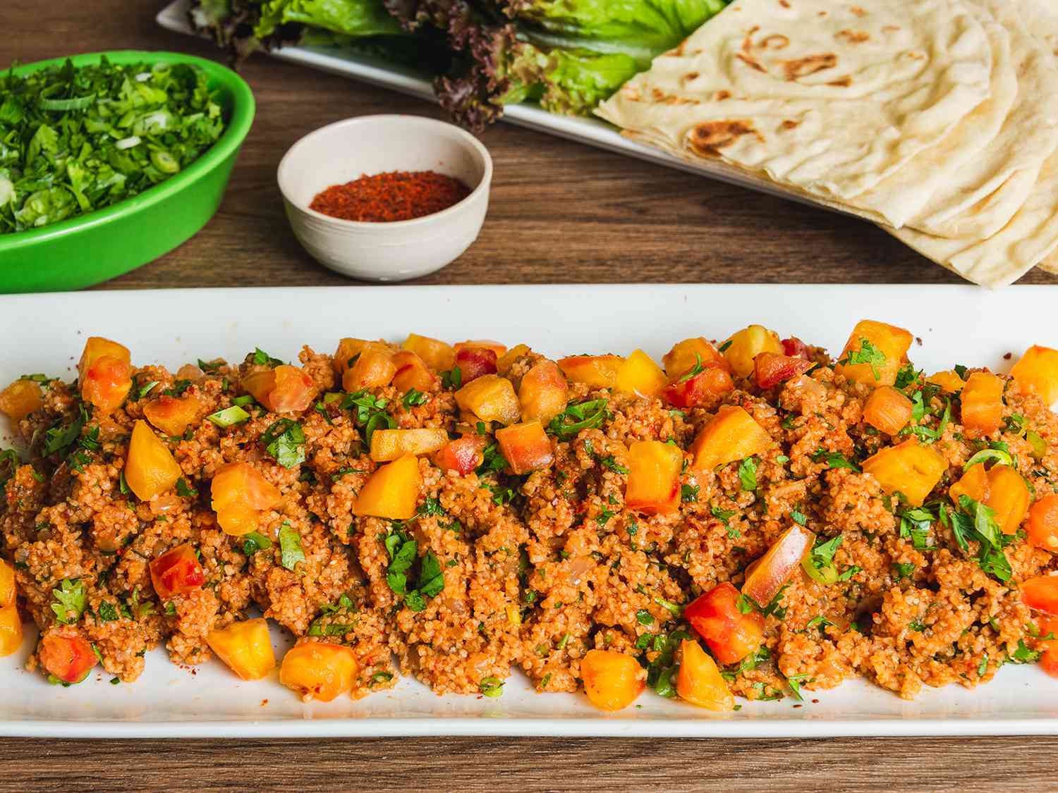 Platter of eetch served with herb salad, lavash, and lettuces.