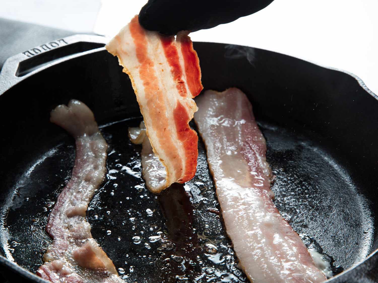 Flipping bacon in a pan.