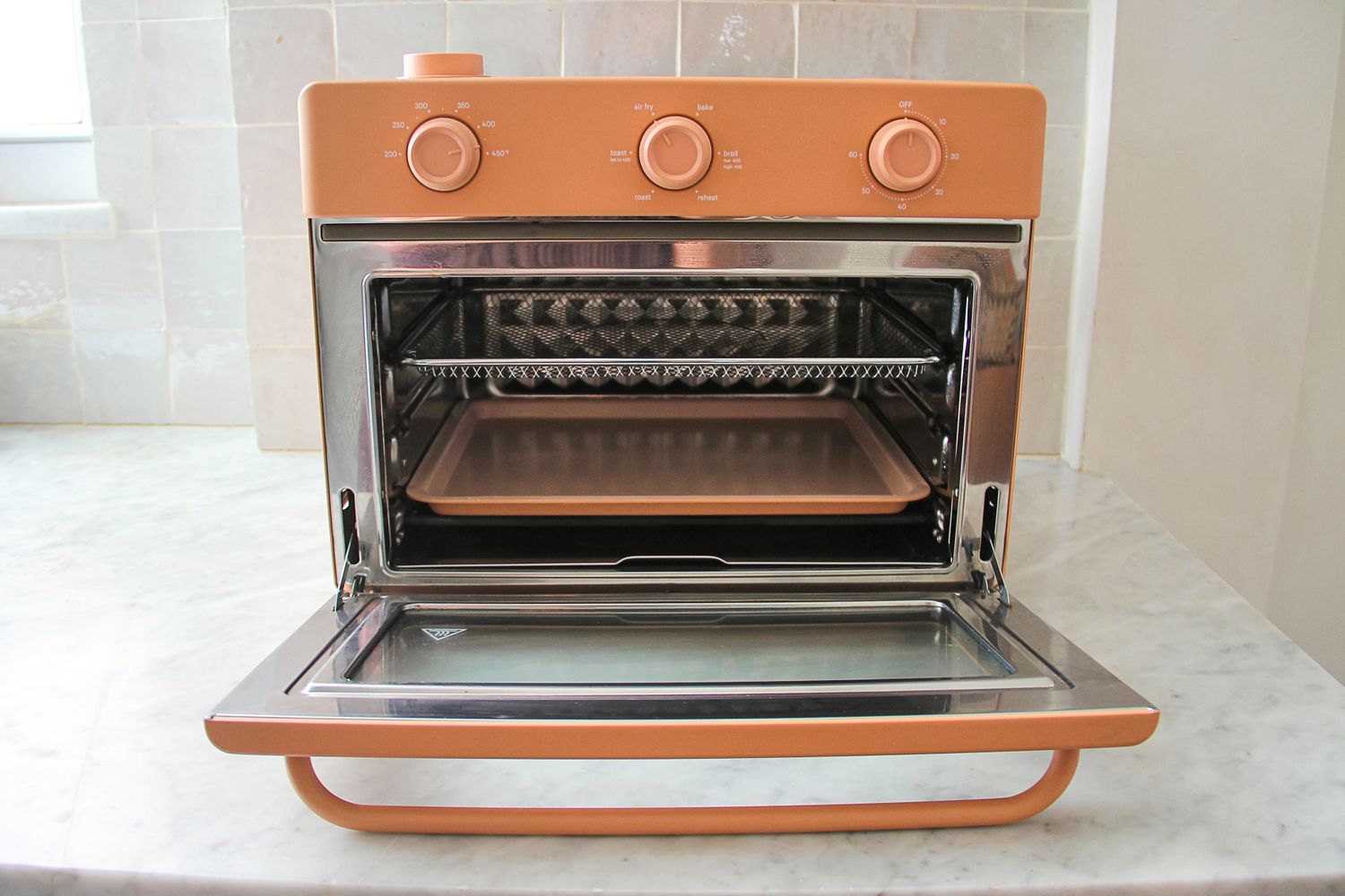 A countertop toaster oven with an open door, showing a baking tray and grill rack inside