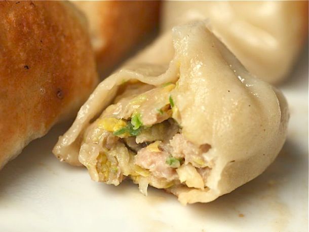 A cooked dumpling with a bite out of it, showing the tender interior.