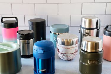 Food thermoses displayed against a white tile backdrop