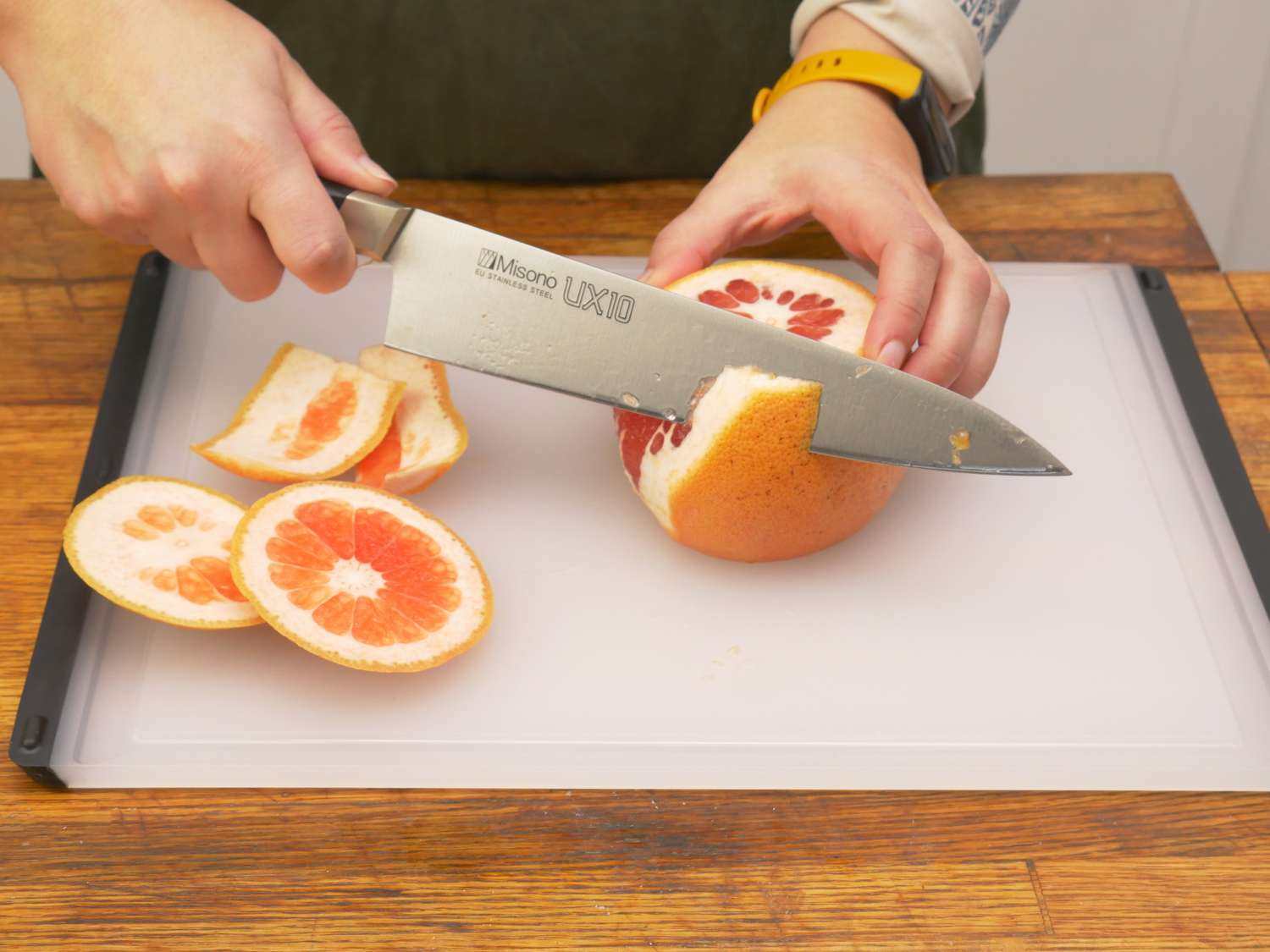 a person removing the peel from a grapefruit on the oxo board