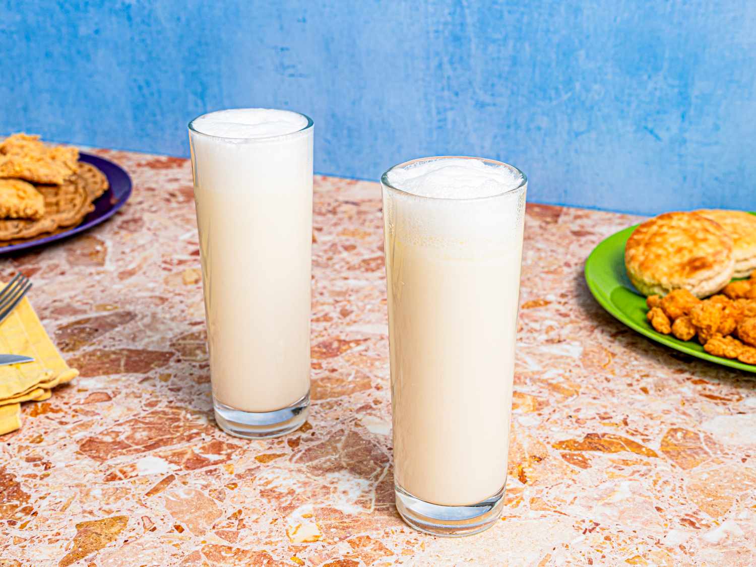 Two Ramos Fizz cocktails, served with brunch food in the background