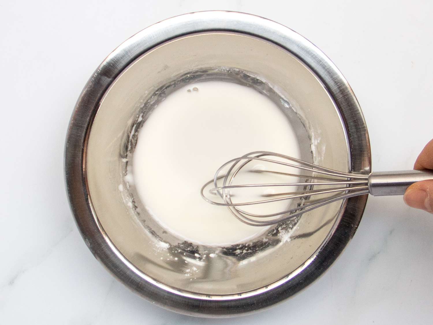 Corn starch and water whisked together in a stainless steel bowl.