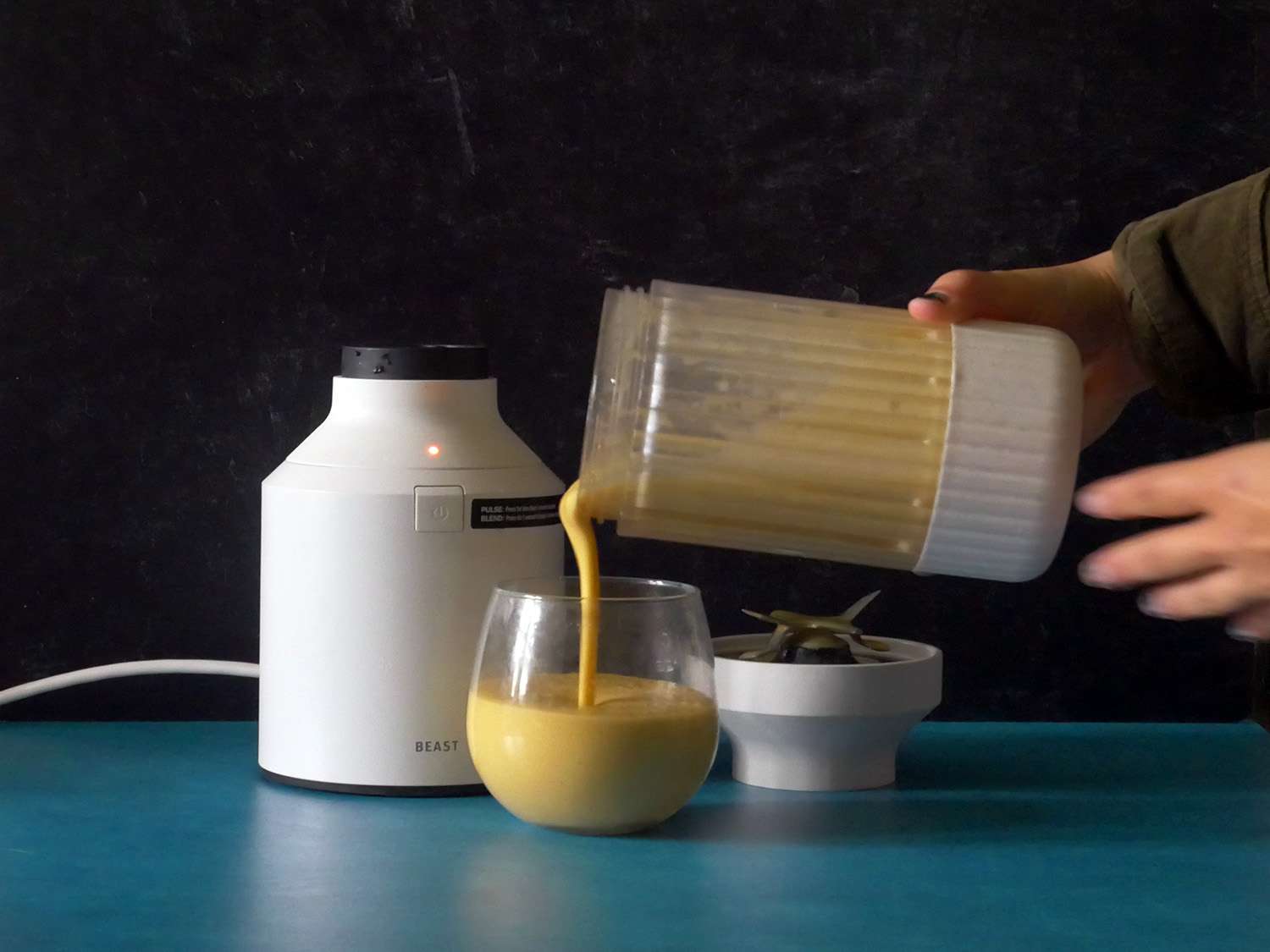 pouring a smoothie out of the blender jar into a cup