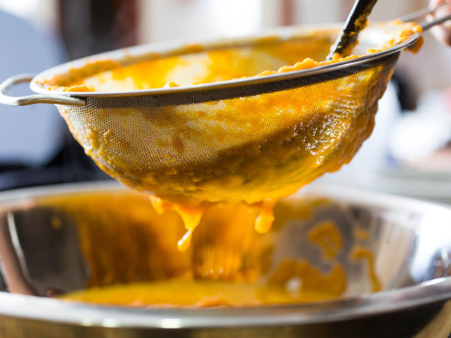 Straining sweet potato soup through a fine-mesh strainer. 