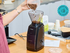 A person pours coffee beans into the Baratza Encore coffee grinder