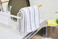 A striped dish towel hanging off of a dish rack.