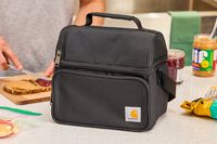 Black Carhartt lunch box on a countertop in front of a person making a sandwich