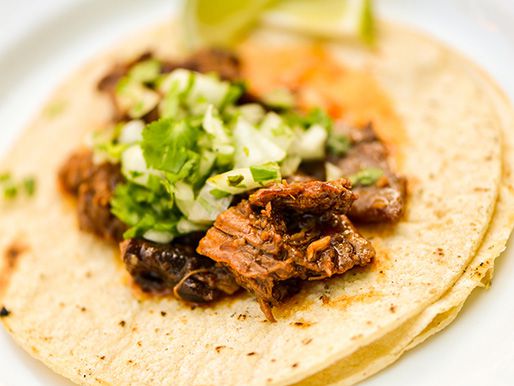 Closeup of the smoked lamb barbacoa served in a taco with cilantro and onion.