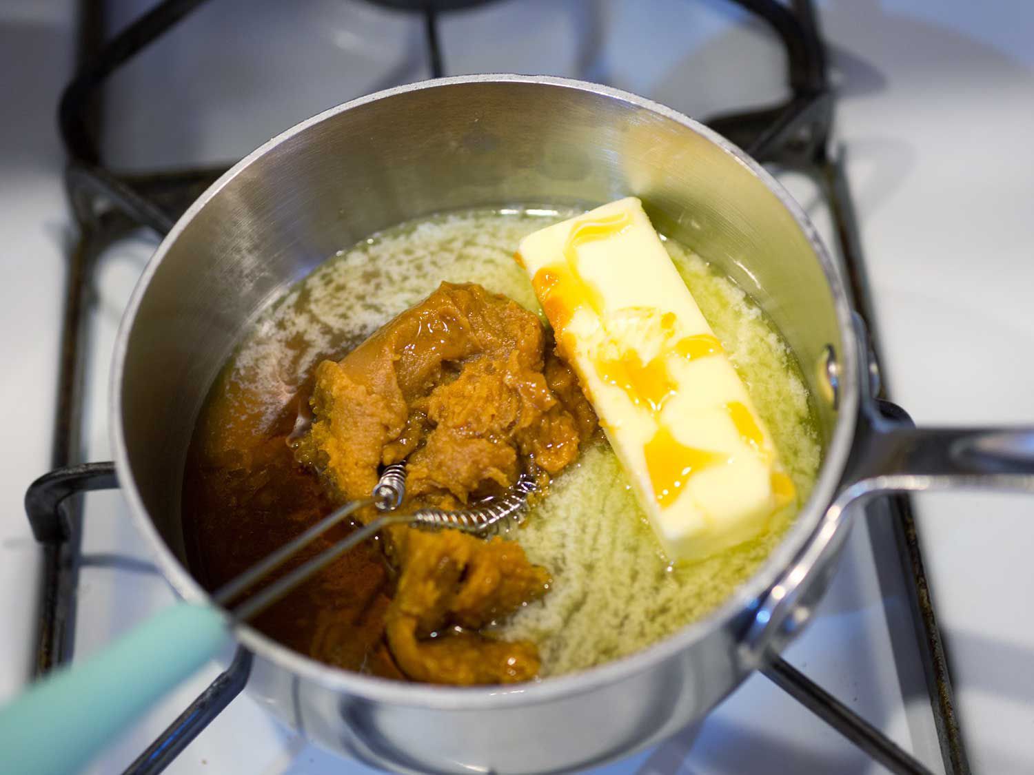 Melting butter and miso are whisked together in a small saucepan.