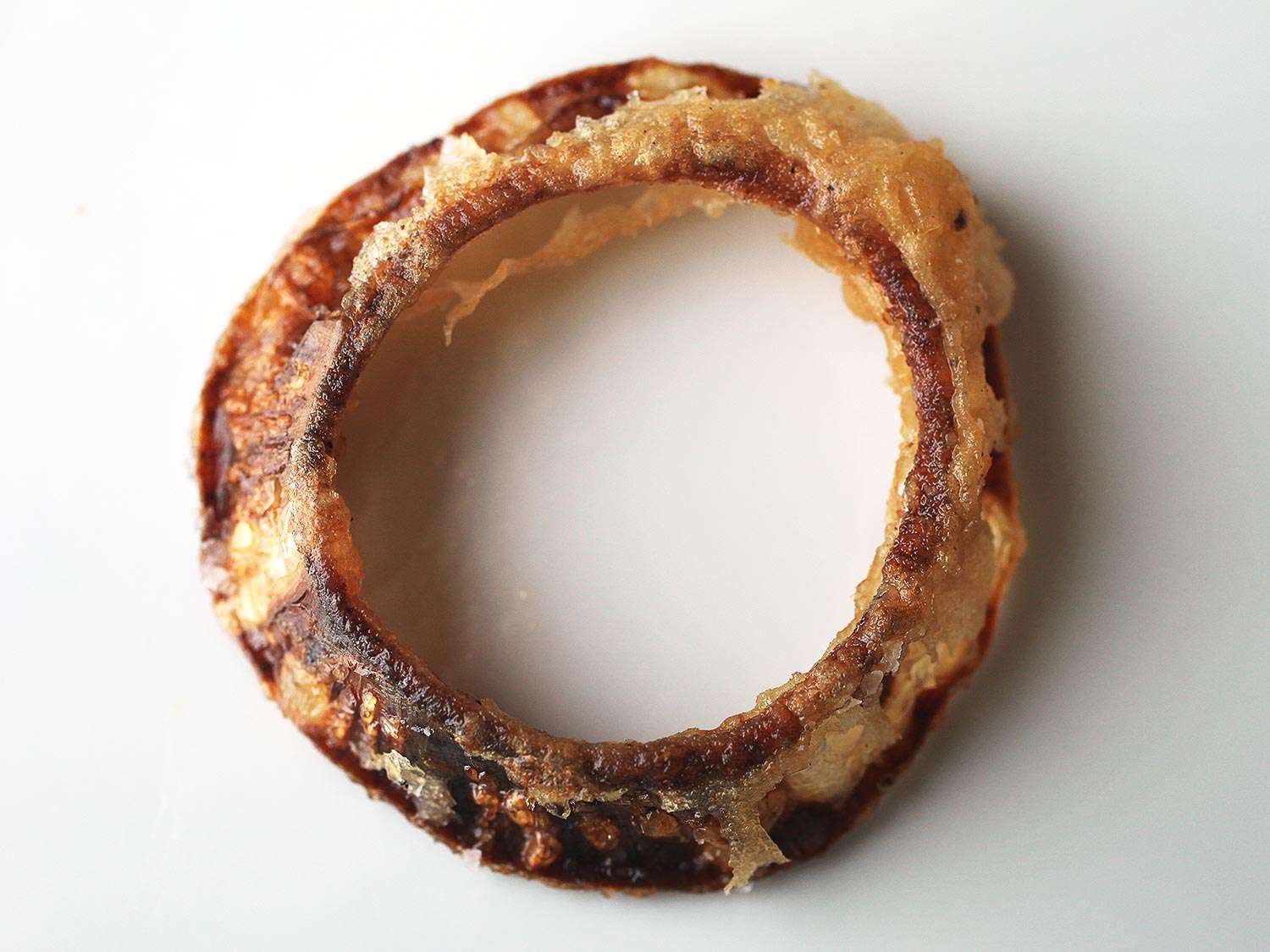 An under-battered onion ring. The exposed onion flesh has darkened considerably.