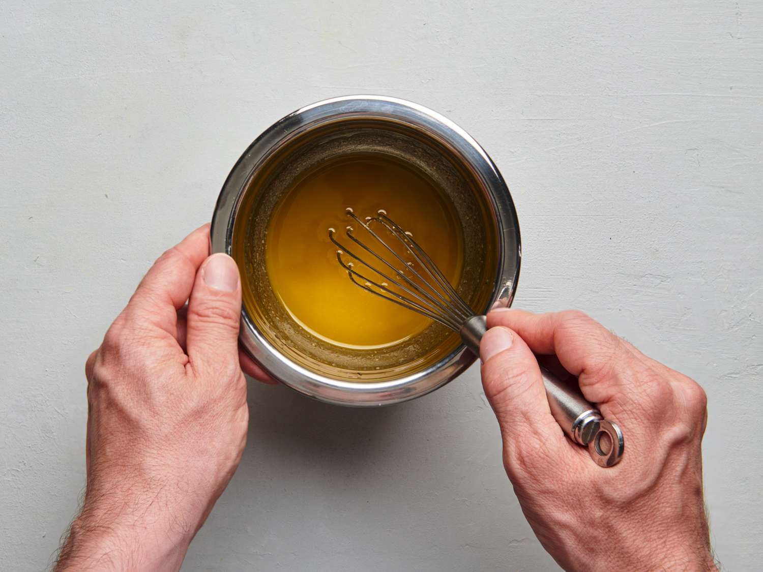 Olive oil, sherry vinegar, mustard, and honey whisked together and seasoned inside a small bowl.