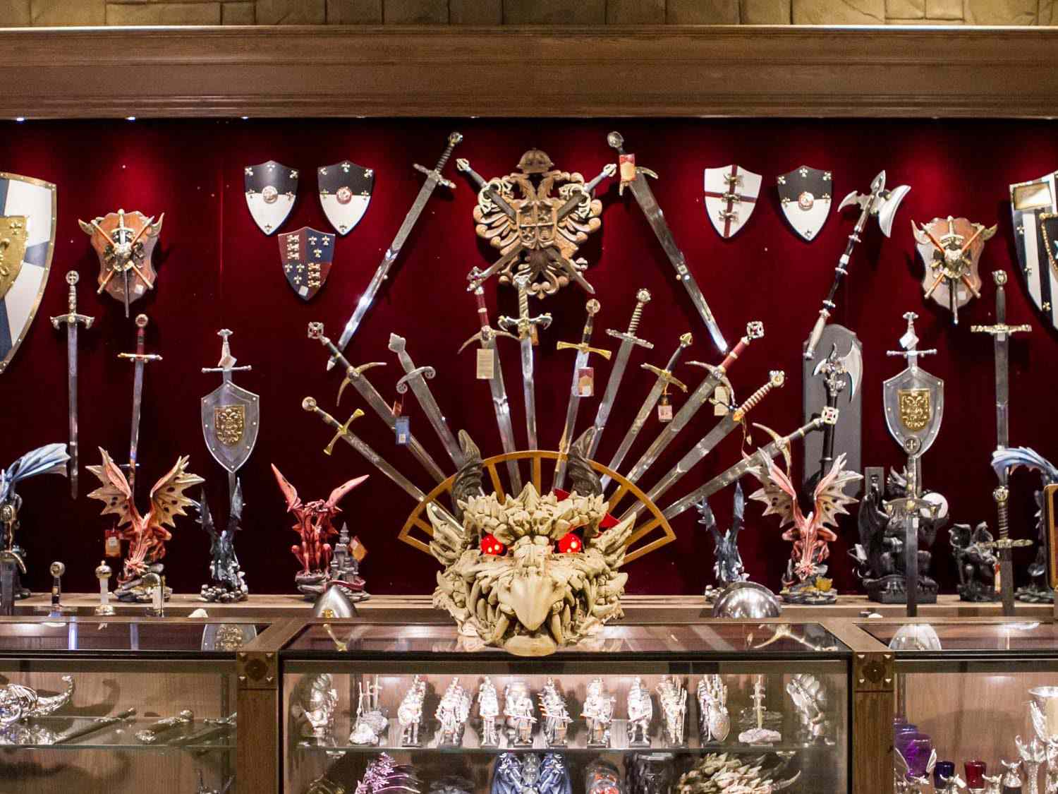 Items at the Medieval Times gift shop: an array of swords, shields, and axes displayed on the wall, plus dragon figurines and a large 
