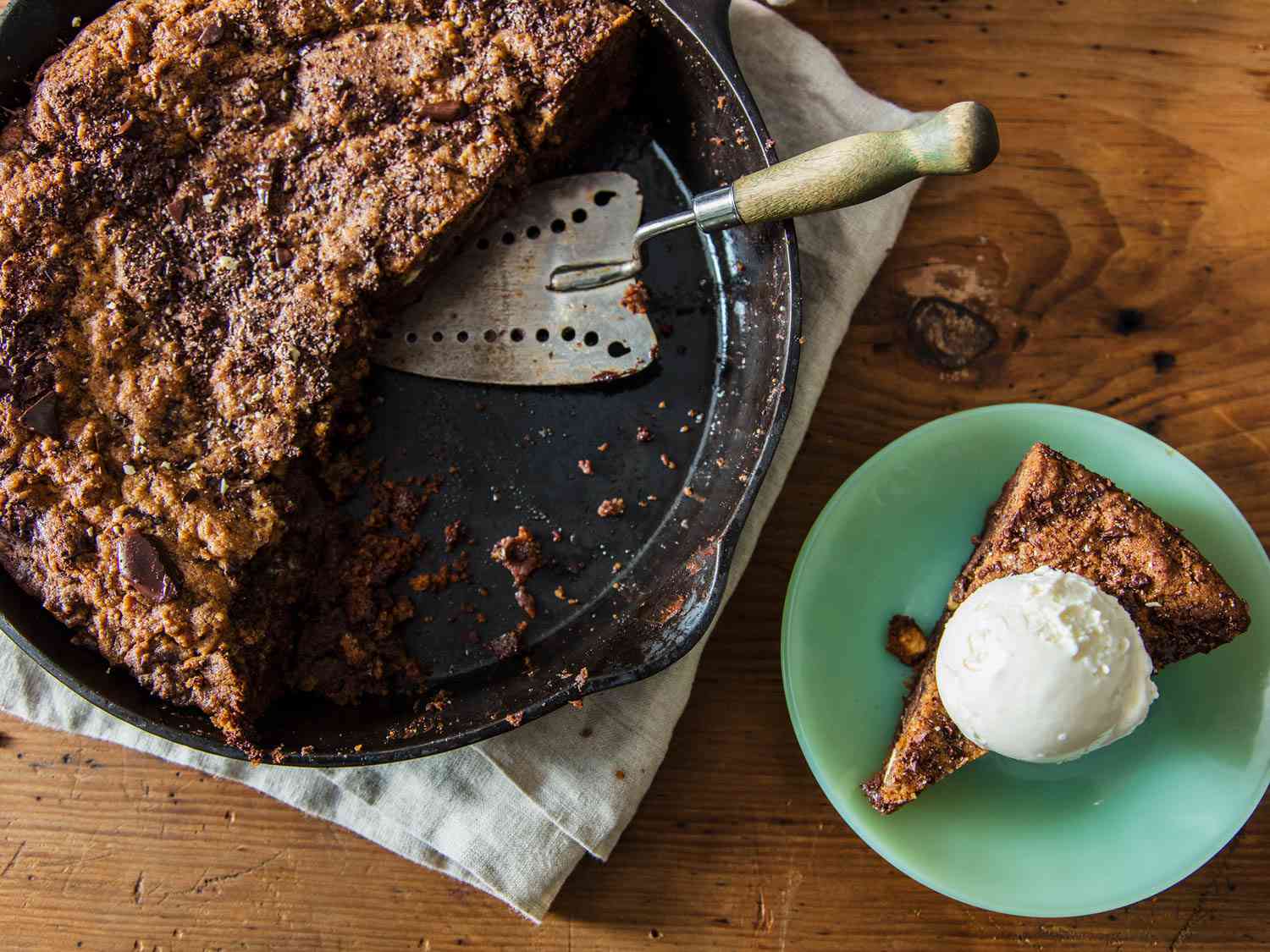 Chocolate chip skillet cookie in skillet and a slice of it on a plate