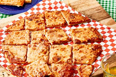 A St Louisstyle pizza sliced into squares on a checkered paperlined wooden board
