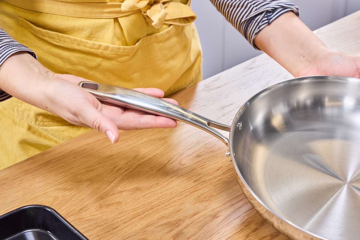 A person holds the handle of the Tramontina 12-Inch Stainless Steel Skillet