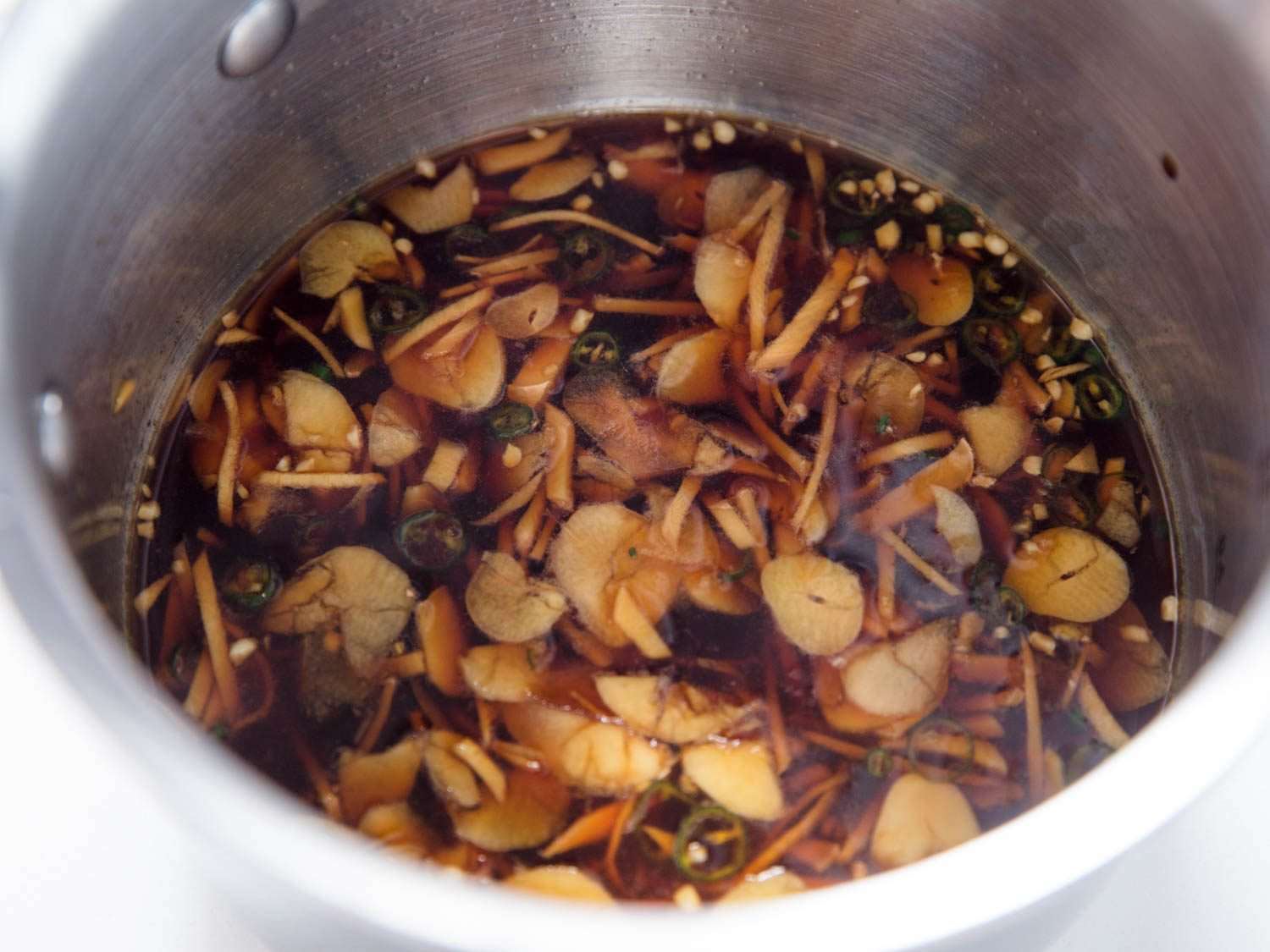 The warmed dressing, packed with sliced garlic and ginger matchsticks.