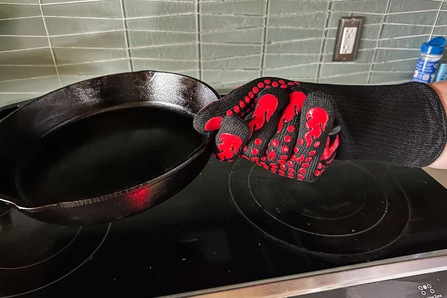 A person holds a cast iron pan while wearing the Comsmart BBQ Gloves