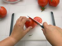 a person slicing a tomato