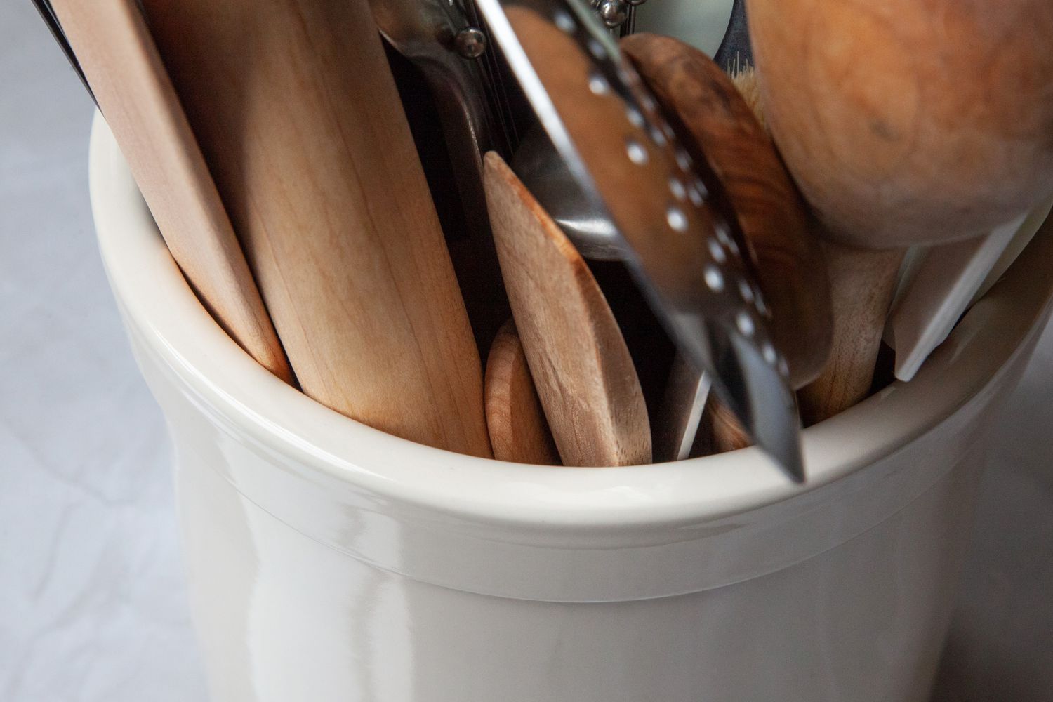 A utensil crock filled with various wooden and metal cooking tools.