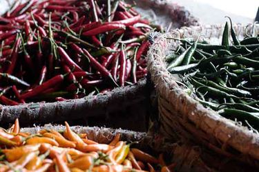 Three large baskets with filled small red, green, and orange hot chiles.