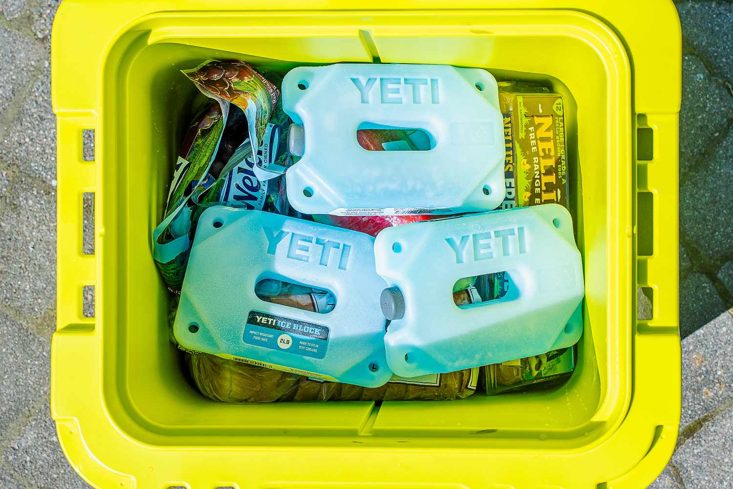 A cooler containing Yeti ice packs and food items arranged inside