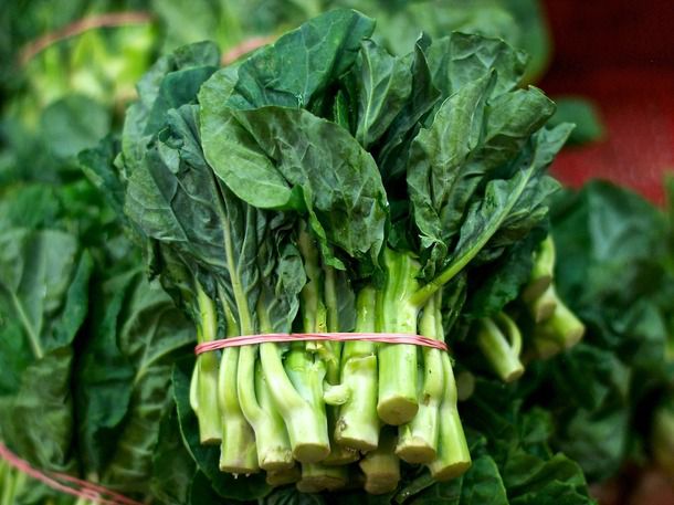 A bundle of Chinese broccoli held together with a rubber band 