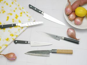 five petty knives on a white tile surface