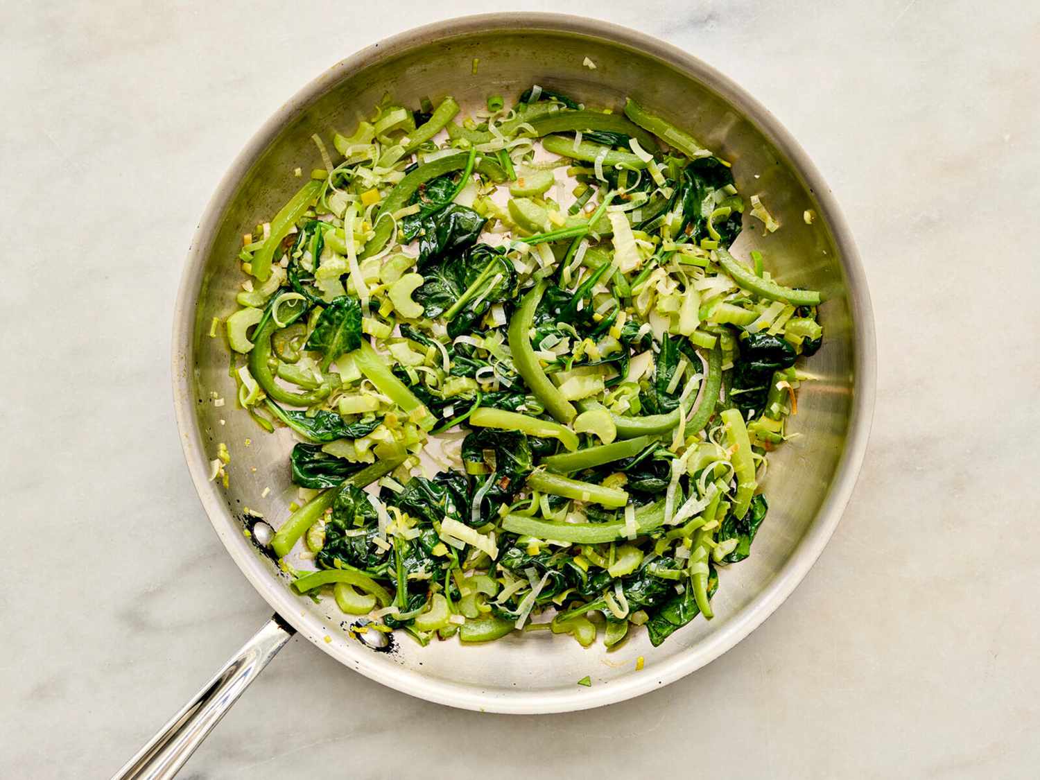 Celery and leek sauteeing in skillet 