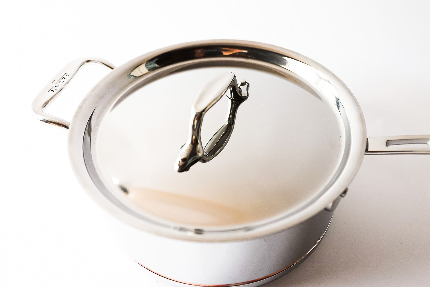 A stainless steel pot with a lid and side handles