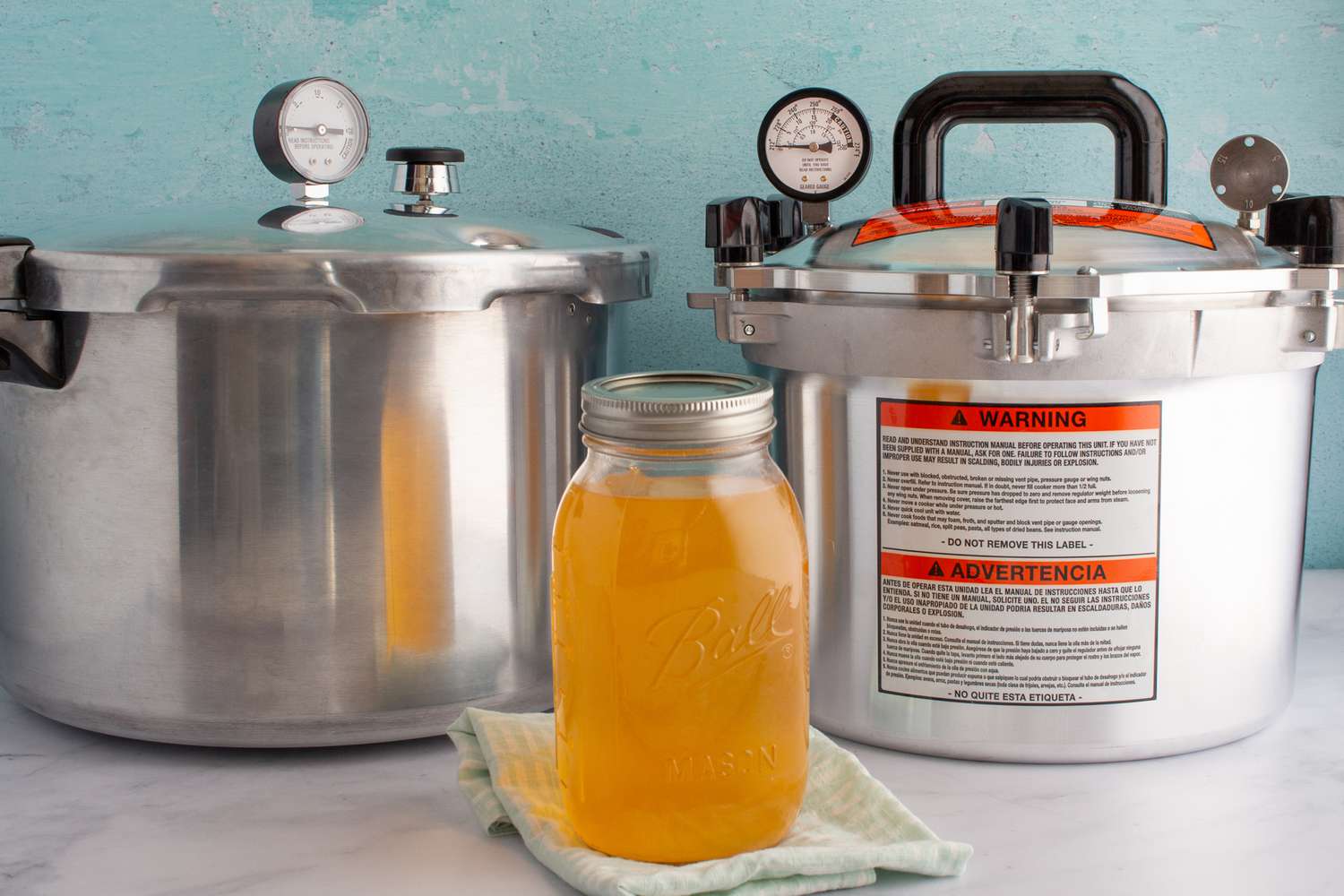A jar of chicken stock in front of two pressure canners