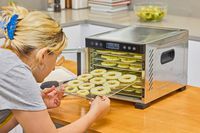 A person placing apple rings inside the Magic Mill 7 Tray Pro Food Dehydrator Machine