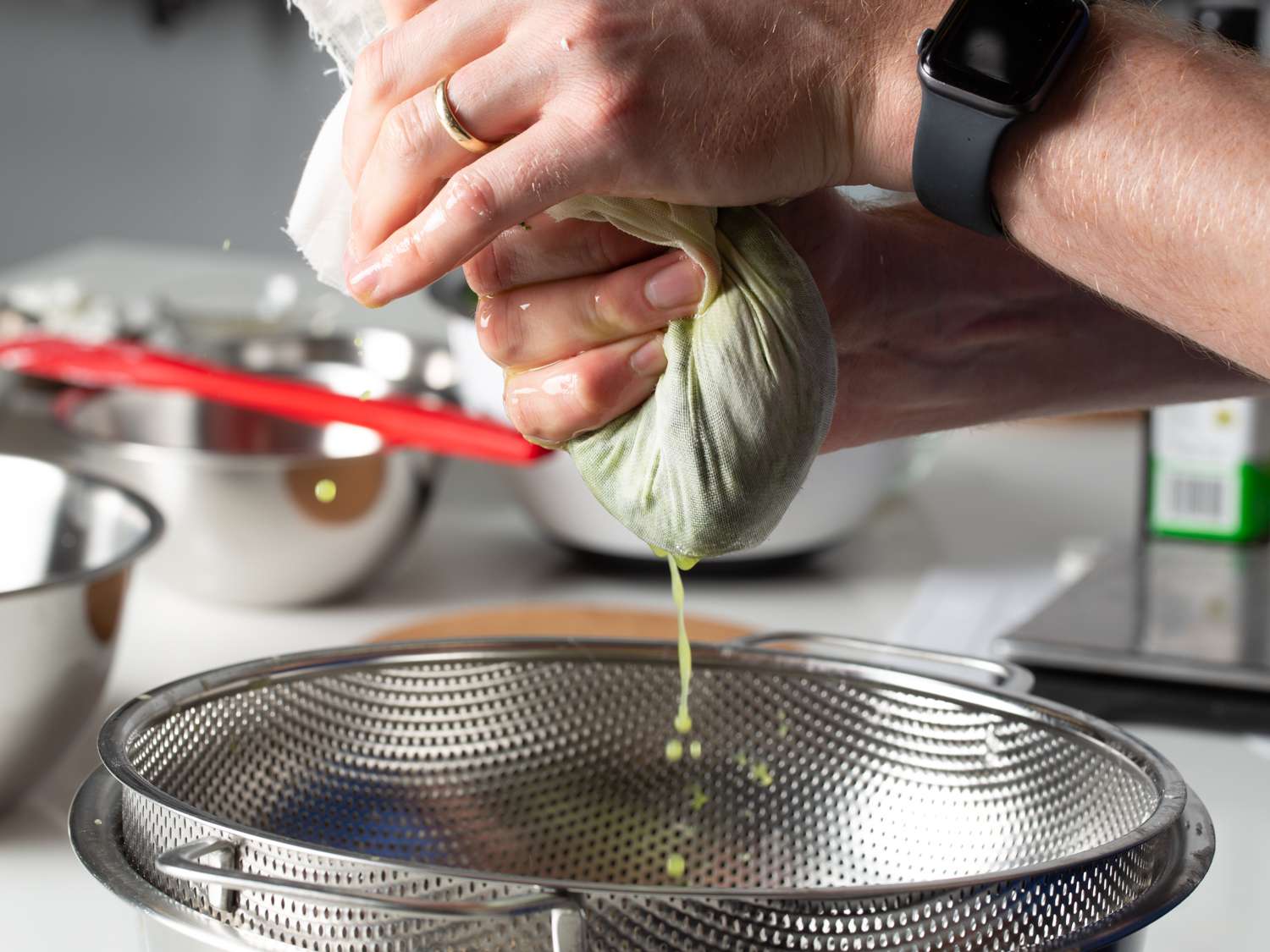 squeezing excess moisture from spinach through a cheesecloth