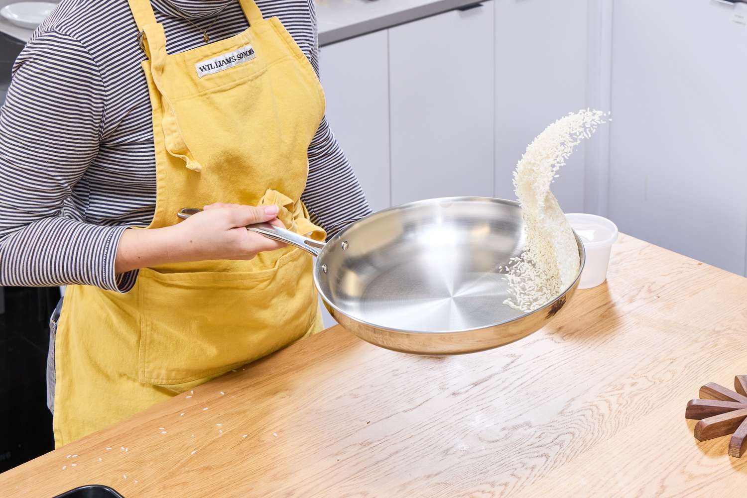 A person tossing rice in the Tramontina 12-Inch Stainless Steel Skillet