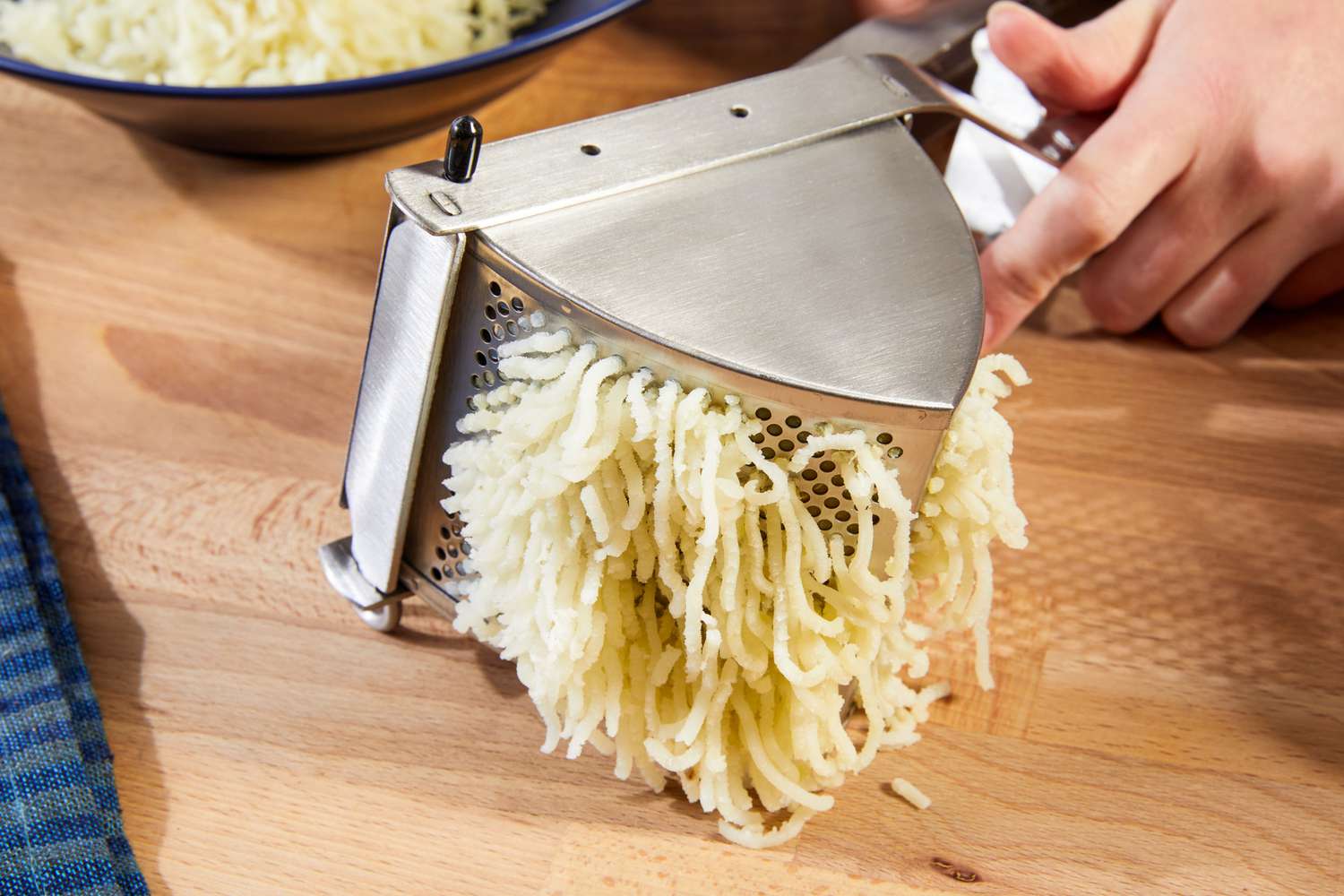 A potato ricer ricing potatoes.
