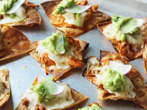 Individually-topped chicken tinga nachos with cheese, guacamole and sliced radish.