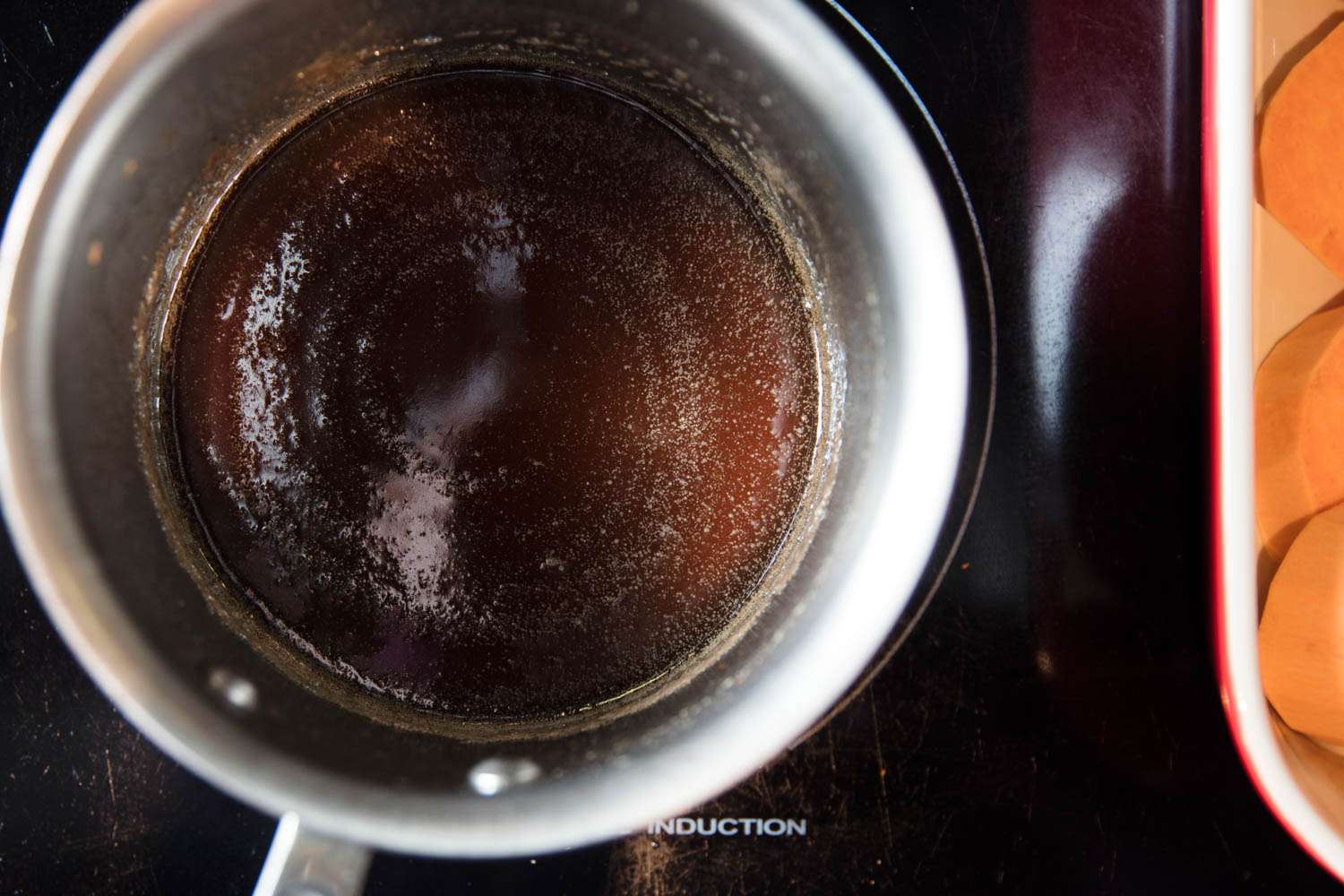 Simmering a small saucepan of syrup on a cooktop for candied yams (sweet potatoes).