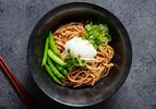 A bowl of mazemen ramen topped with an egg, snap peas, and sprouts
