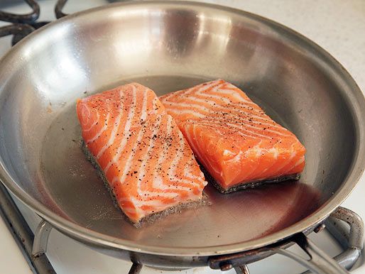 Pan-roasting salmon fillets in a stainless steel skillet.