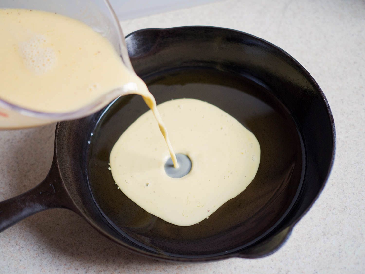 Pouring farinata batter into a cast iron skillet. 