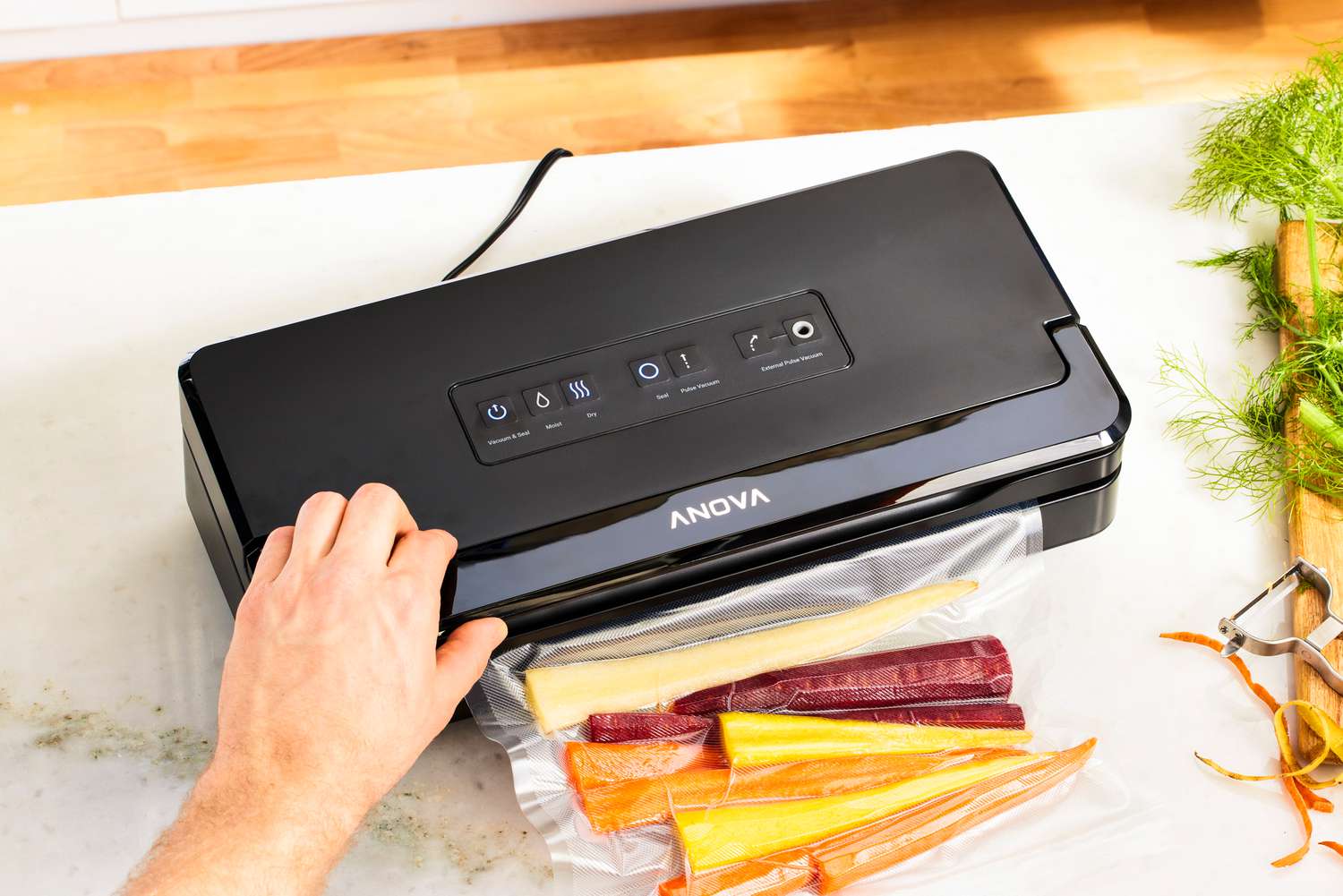 A person using a vacuum sealer to seal a bag of rainbow carrots.