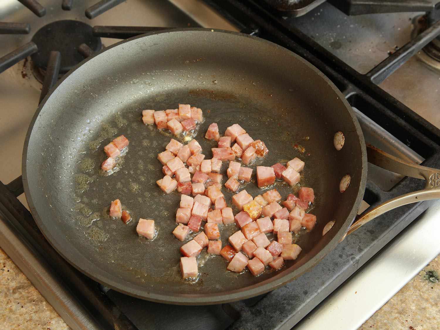 Cubes of ham browning in a nonstick skillet.