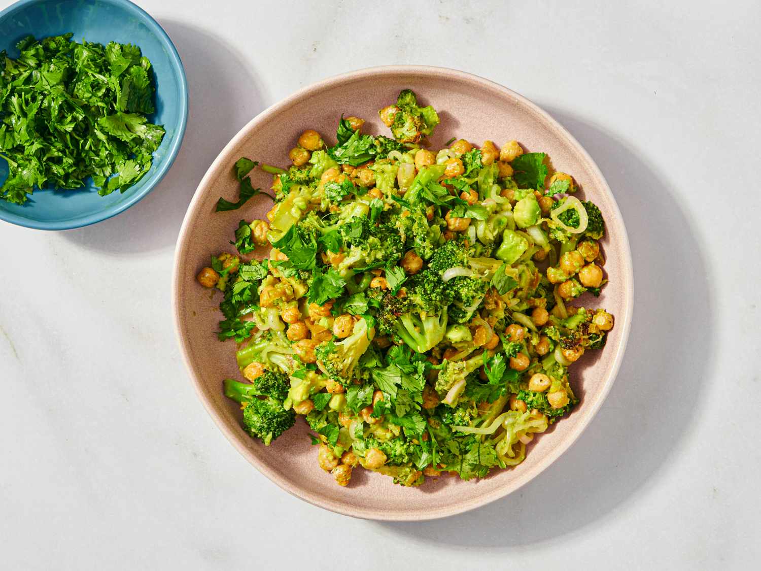 Plate of broccoli and chickpeas with a side dish of leafy herbs