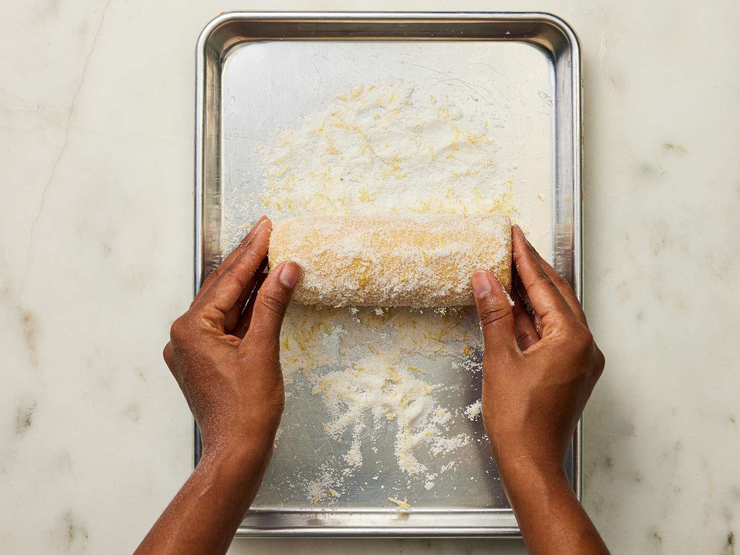 Rolling frozen dough in sugar mixture on a metal sheetpan 