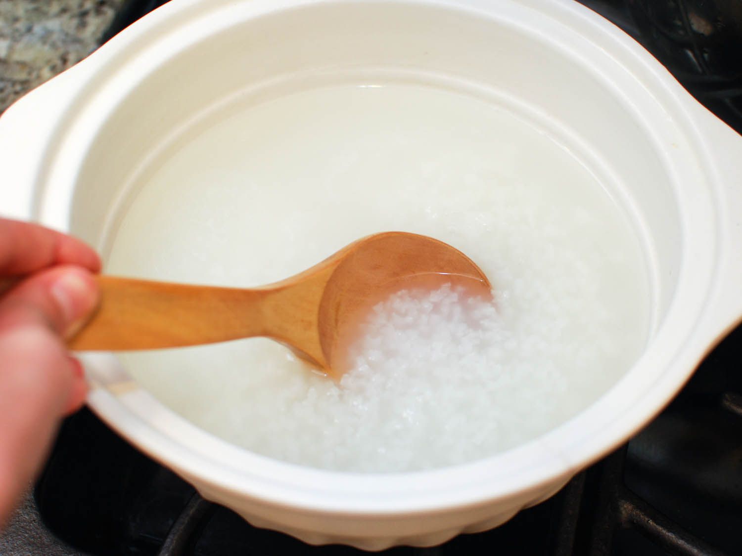 Stirring short grain rice in water for congee. 