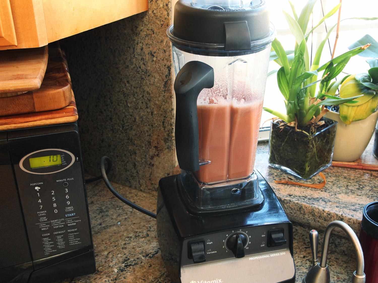 Blending anchovies, tomato paste, Worcestershire sauce, soy sauce, and chicken broth in a Vitamix blender.